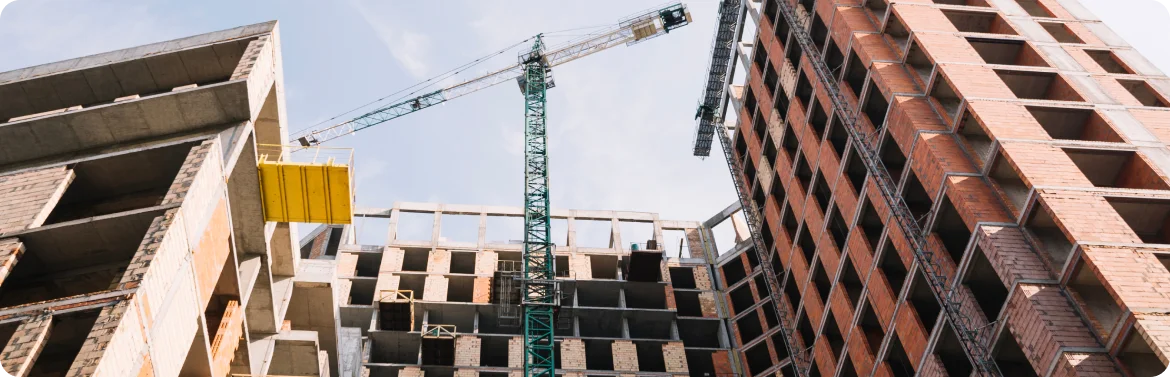 Moderne meerlaagse gebouwen in aanbouw op een bouwplaats met kranen en structurele frameworks.