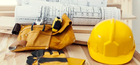 Beschermende uitrusting, blauwdrukken, handschoenen en gereedschap voorbereid voor een woning- of commercieel bouwproject.